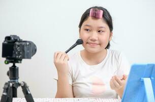 söt asiatisk kvinna bloggare är som visar på vilket sätt till göra upp och använda sig av kosmetika. foto