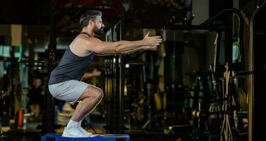 caucasian man med stark och muskulös fast form är Träning på ben dag förbi håller på med förskott hoppa knäböj för lår och kalv muskel i Gym för friska och stark lägre kropp vikt styrka med kopia Plats foto