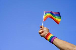 människor hand innehav HBTQ färgrik regnbåge Gay flagga bakgrund blå himmel, koncept av lgbtq mångfald kön kärlek, aktivist, rättigheter, protest, rörelse parad, fira, festival foto