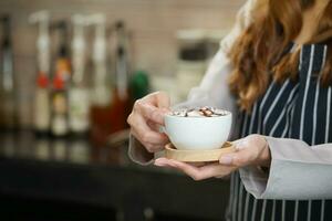 Barista hand innehav en kopp av varm kaffe till tjänande kund foto