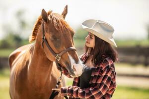 brun häst lutar mot en cowgirl på en ranch innan hästridning foto