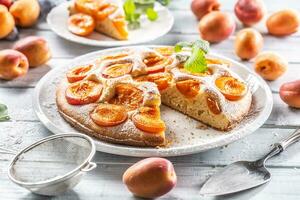 aprikos paj på en vit tallrik, aprikoser, mynta och pulveriserad socker på de kök tabell foto