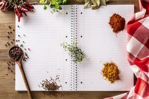 öppen anteckningsbok med kryddor och örter, chili, oregano, curry, basilika, kummin ,bukt blad, och rosmarin foto
