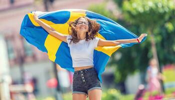 Lycklig flicka turist gående i de gata med Sverige flagga foto