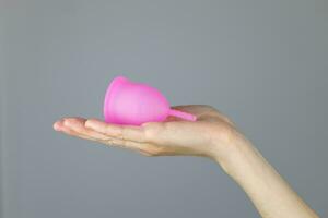 närbild av en kvinnas händer innehav en silikon menstruations- kopp. alternativ ekologisk feminin hygien produkt under menstruation utan avfall begrepp foto