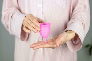 närbild av en kvinnas händer innehav en silikon menstruations- kopp. alternativ ekologisk feminin hygien produkt under menstruation utan avfall begrepp foto