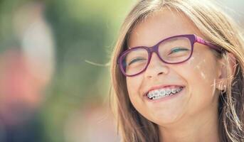 porträtt av en Lycklig leende Tonårs flicka med dental tandställning och glasögon foto