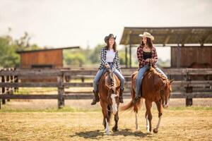 två cowgirls ridning deras hästar på en ranch under varm sommar dag foto