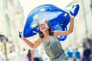 eu flagga. söt Lycklig flicka med de flagga av de europeisk union. ung Tonårs flicka vinka med de europeisk union flagga i de stad foto