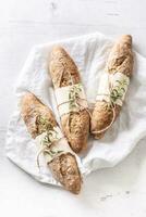 topp se av tre baguetter eller fullkorn bröd på en Linné textil- vit yta foto