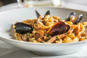 italiensk pasta med musslor och räka i vit tallrik foto