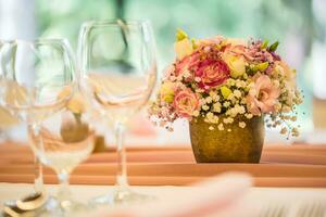 bröllop tabell miljö. skön tabell uppsättning med blommor och glas koppar för några festlig händelse, fest eller bröllop reception foto