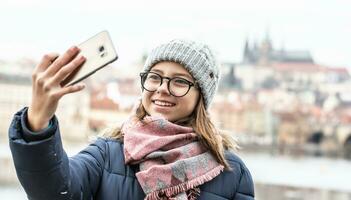 Tonårs flicka i glasögon tar en selfie i prag på en kall vinter- dag foto