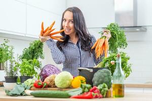 lekfull ung kvinna i henne kök innehav färsk morot i både händer - diet vegetabiliska och hed begrepp foto