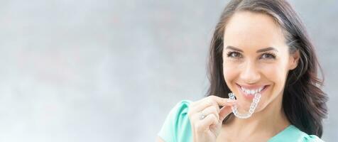 invisalign ortodonti begrepp - ung attraktiv kvinna innehav - använder sig av osynlig tandställning eller tränare foto