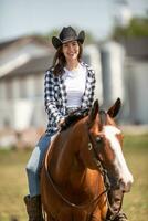 skön leende flicka ridning en måla häst, bär en svart cowboy hatt foto