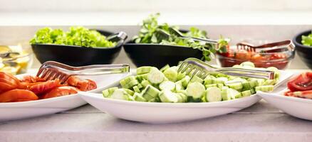 färsk grönsaker, gurkor, tomater och sallad i skålar på buffé tabell i hotell restaurang foto