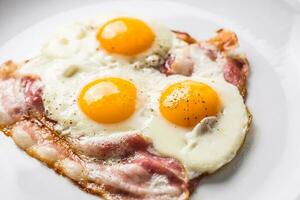 skinka och ägg. bacon och ägg. saltade ägg med peppar på vit tallrik. engelsk frukost foto