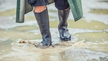 en man med svart stövlar promenader på en översvämmad väg foto
