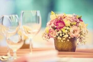 bröllop tabell miljö. skön tabell uppsättning med blommor och glas koppar för några festlig händelse, fest eller bröllop reception foto