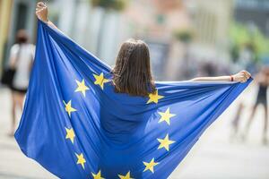 söt Lycklig ung flicka med de flagga av de europeisk union i de gator någonstans i Europa foto