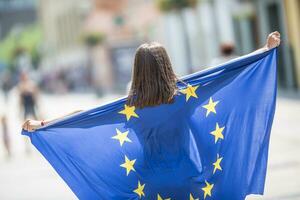 söt Lycklig ung flicka med de flagga av de europeisk union i de gator någonstans i Europa foto