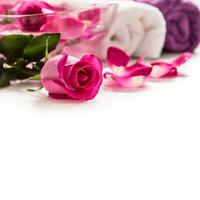 rosa ro kronblad i skål med handdukar och ren vatten över vit.. spa och wellness begrepp foto