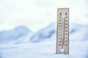 termometer på de bergen i de snö visar temperaturer Nedan noll. låg temperaturer i grader celsius och Fahrenheit foto