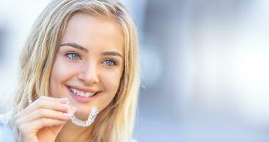 invisalign ortodonti begrepp - ung attraktiv kvinna innehav - använder sig av osynlig tandställning eller tränare foto