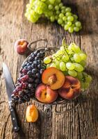 mogen vindruvor och persikor i rustik skål och trä- tabell foto