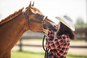 ungdom flicka kyssar en brun häst uttrycker kärlek mot de djur foto