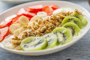 friska frukost eras med tallrik av yoghurt mysli kiwi jordgubbar och banan foto