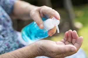 asiatisk senior eller äldre gammal damkvinna som tvättar hand med blå alkoholreningsgel för att skydda säkerhetsinfektion och döda covid-19-coronavirus, bakterier och bakterier.