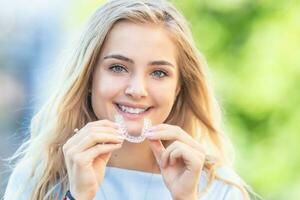 invisalign ortodonti begrepp - ung attraktiv kvinna innehav - använder sig av osynlig tandställning eller tränare foto