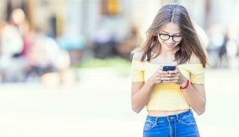 ung studerande flicka textning på henne smartphone och leende foto