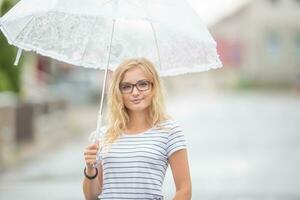 skön ung blond flicka innehav paraply i sommar regn foto