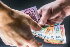 manlig händer innehav euro sedlar och de Övrig hand till motta en muta foto