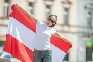 ung kvinna utomhus innehar en flagga av Österrike, leende foto