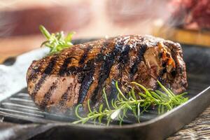 grillad nötkött biff i grill panorera med örter rosmarin på trä- tabell foto