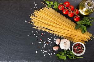 pasta och matlagning ingredienser på svart skiffer bakgrund. foto