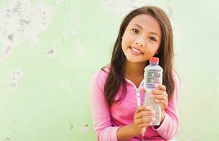 asiatisk ung flicka innehav en vatten flaska foto