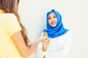 en kvinna bär en blå hijab är undviker ett äpple foto