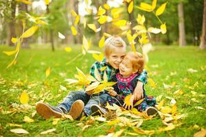två barn spelar i de gräs med löv foto