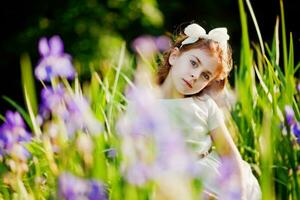 en liten flicka är stående i de gräs med henne händer på henne huvud foto