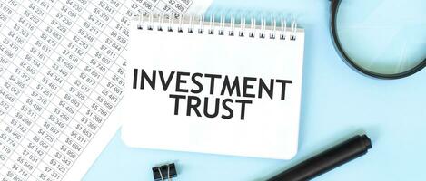 vit anteckningsblock och förstoringsglas på de finansiell dokumentation. text investering förtroende. företag begrepp foto