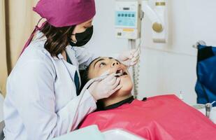 dental specialist rengöring de tänder av en kvinna patient. professionell tandläkare rengöring en kvinna patientens mun, kvinna tandläkare rengöring och granskning en kvinna patientens mun foto