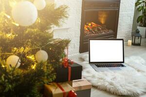 bärbar dator står nära de öppen spis och jul träd foto