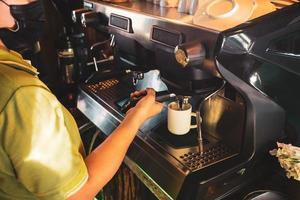 barista, asiatisk kvinna som brygger kaffe med en kaffemaskin. för att starta ett litet företag inom livsmedelsindustrin koncept. foto