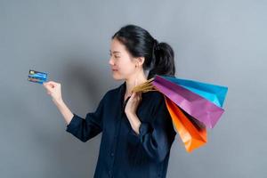 vacker asiatisk kvinna med kassar och visar kreditkort