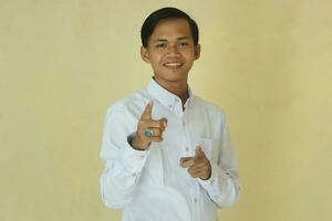 ung asiatisk man i vit skjorta pekande framåt- ger rösta eller hålla med på gul bakgrund foto